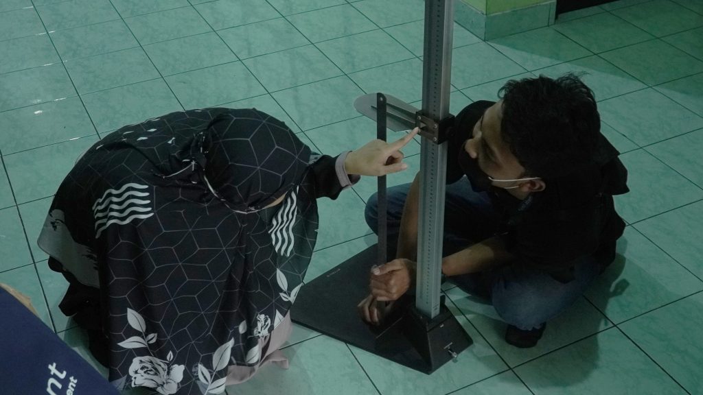 Sigit Dwi Prasetyo melakukan uji pengukuran stadiometer portable  dengan penggaris disaksikan oleh dr. Neti Nurani, Sp. A (K), M.Kes pada Selasa (22/2/22)  